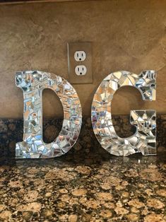 the letters c and g are made out of glass mosaic tiles on a granite countertop