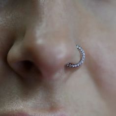 a close up view of a person's nose with an ear piercing in the shape of a crescent