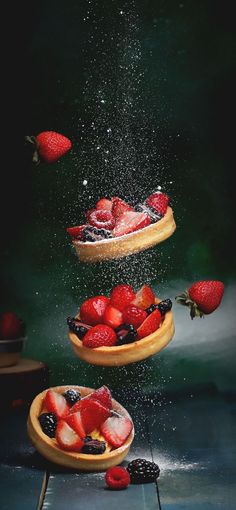 strawberries are falling into the air on wooden plates