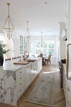 a large kitchen with marble counter tops and white cabinets, along with an area rug on the floor