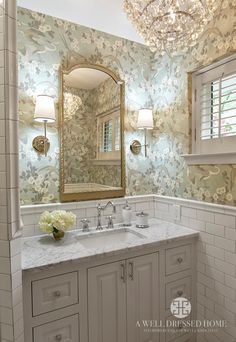 an image of a bathroom with marble counter tops and white cabinets, along with a large mirror above the sink