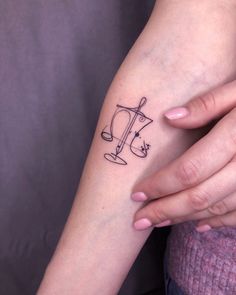 a woman's arm with a tattoo on it that has the letter j in black ink