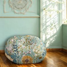 a round cushion sitting on top of a hard wood floor in front of a window