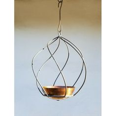 a bowl hanging from a wire on a white wall with a light in the background