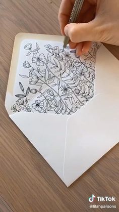 someone is drawing flowers on top of an envelope