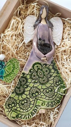 a ceramic figurine sitting on top of a green leaf in a cardboard box