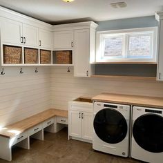 a washer and dryer in a small room with white cabinets on the walls