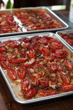 two pans filled with cooked tomatoes on top of a table