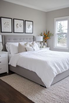 a white bed sitting in a bedroom next to two framed pictures on the wall above it