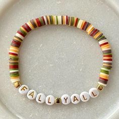 a white plate topped with a colorful beaded bracelet and nameplates on it