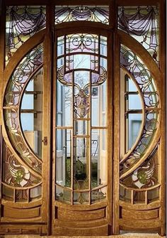 an ornately designed wooden door with glass inserts on the top and bottom panels