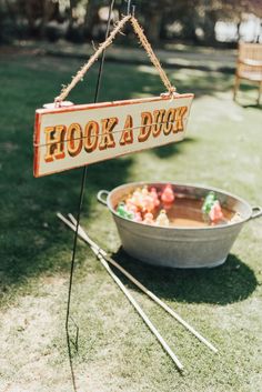 a sign that says hook a duck hanging from a rope next to a bucket full of food