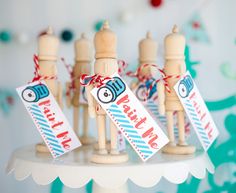 small wooden toy figurines with tags attached to them on a white cake plate