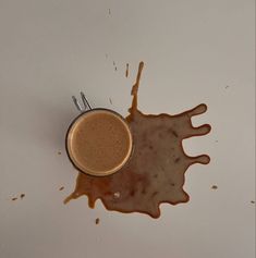 a cup of coffee sitting on top of a white table next to a spoon and saucer