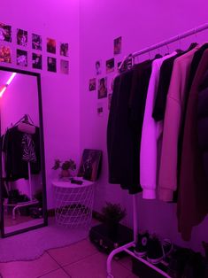 a room with purple lighting and clothes hanging on the rack in front of a mirror