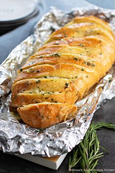 a loaf of bread sitting on top of aluminum foil covered in herbs and seasoning