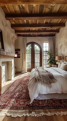 a large bed sitting in the middle of a bedroom next to a fireplace and windows