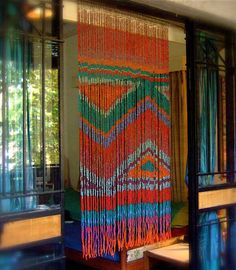 a multicolored wall hanging in front of a window