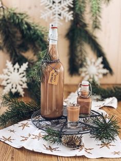 a bottle of hot chocolate sitting on top of a table next to some pine branches