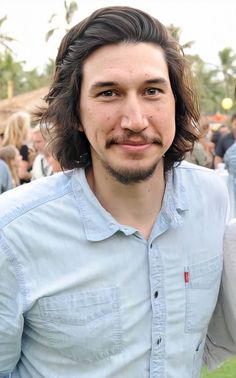 a man with long hair and beard standing in front of a crowd at an outdoor event