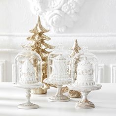 three white and gold christmas cakes under glass domes