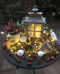 a lit up table with pine cones and lights on it, surrounded by other decorations