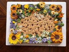 a cake decorated with sunflowers, flowers and crackers on a white plate