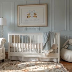 a baby's room with a white crib, chair and framed teddy bear