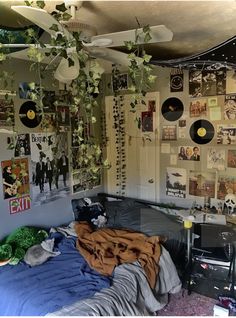 a bed room with a bunch of pictures on the wall and some plants hanging from the ceiling