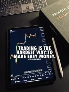 a tablet computer sitting on top of a desk next to a box with trading is the hardest way to make easy money