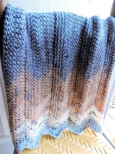 a blue and brown blanket sitting on top of a wooden floor next to a window