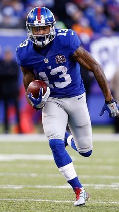 a football player running with the ball in his hand and people watching from the stands