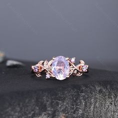 an oval shaped ring with pink stones and leaves on the band, set in gold