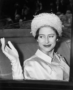 an old photo of a woman wearing a hat and holding her hand up to the camera