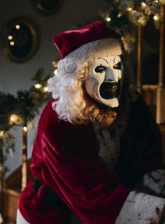 a creepy clown dressed as santa claus in front of a christmas tree