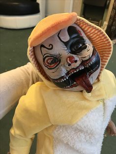 a doll is dressed up as a clown with teeth and mouth painted black, white and orange