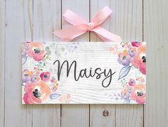 a wooden sign with pink flowers on it that says, maisy written in cursive writing