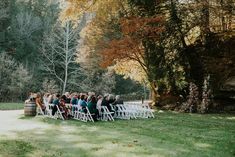 a group of people sitting at a table in the middle of a field with white chairs