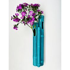 purple flowers are placed in blue vases on the wall