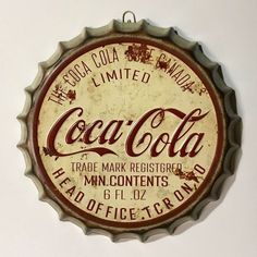 an old coca - cola bottle cap hanging on the wall in front of a white wall