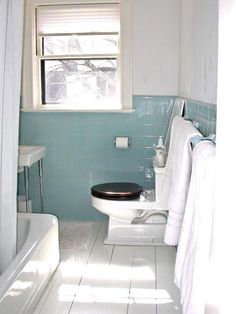 a white toilet sitting in a bathroom next to a bath tub and sink under a window