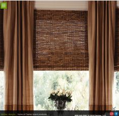 a vase with flowers sitting in front of a window covered in bamboo blinds and drapes