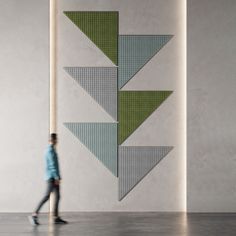 a person walking in front of a wall with an art piece on it's side