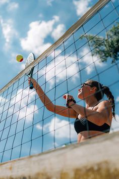 a woman hitting a ball with a tennis racquet on a court in front of the net