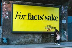 two people standing in front of a large sign on the side of a building that says for fact sake