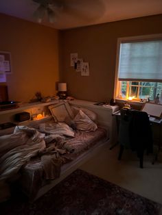 an unmade bed sitting next to a window in a bedroom