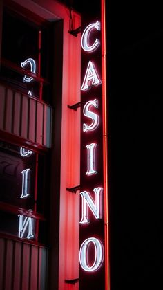 a casino sign lit up at night with neon lights on the side of it's building