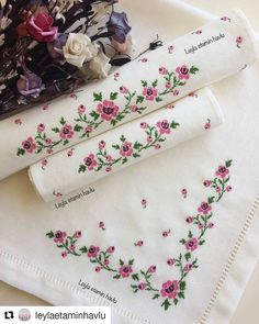 two napkins with embroidered flowers on them sitting on a table next to each other