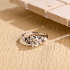 three stone ring sitting on top of a wooden table next to a piece of wood