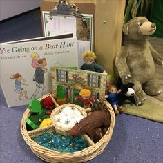 there is a basket with toys and books on the floor next to it, along with two stuffed animals